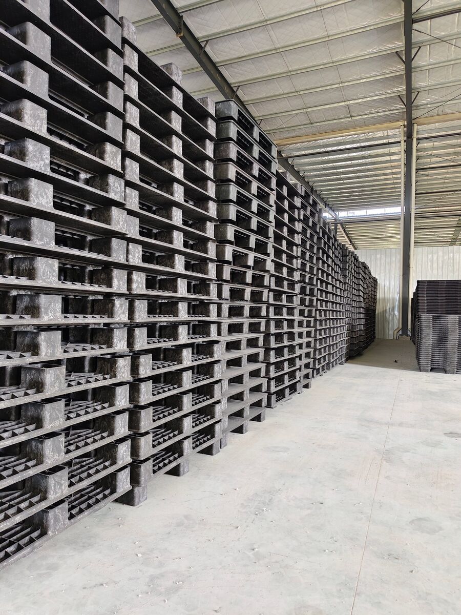 Long stacks of black recycled plastic pallets